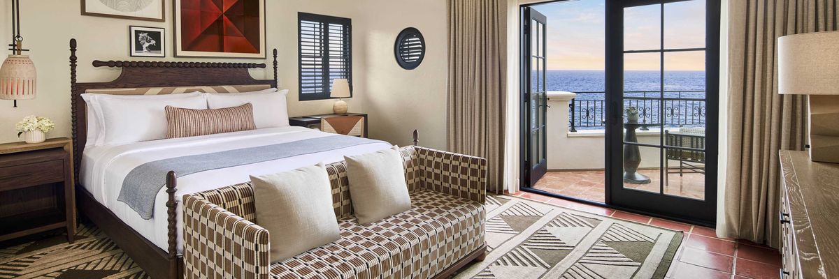 Elegant hotel room with ocean-view balcony, modern decor, and geometric patterns.