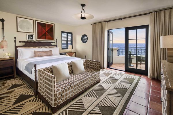 Elegant hotel room with ocean-view balcony, modern decor, and geometric patterns.