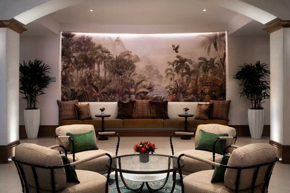Elegant lounge with tropical mural, plush seating, plants, and ambient lighting.