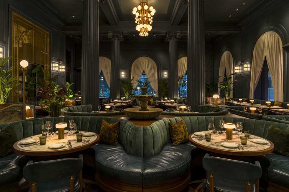 Elegant restaurant interior with round tables, plush seating, and soft lighting.