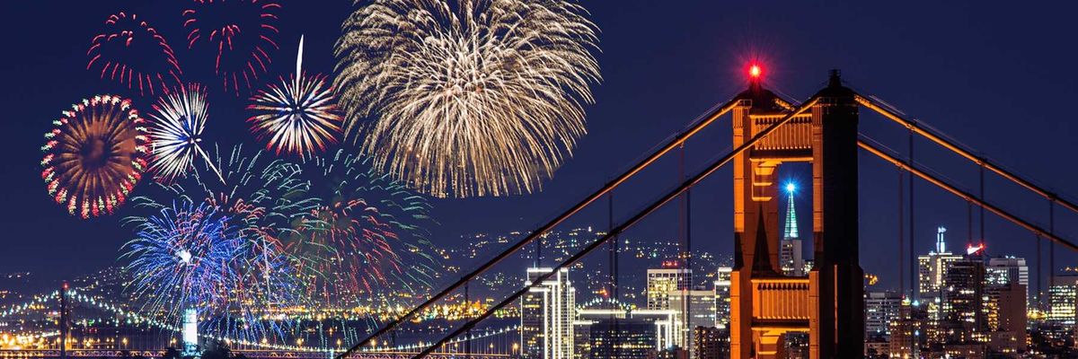 fireworks exploding over the lit up city of san francisco with golden gate bridge