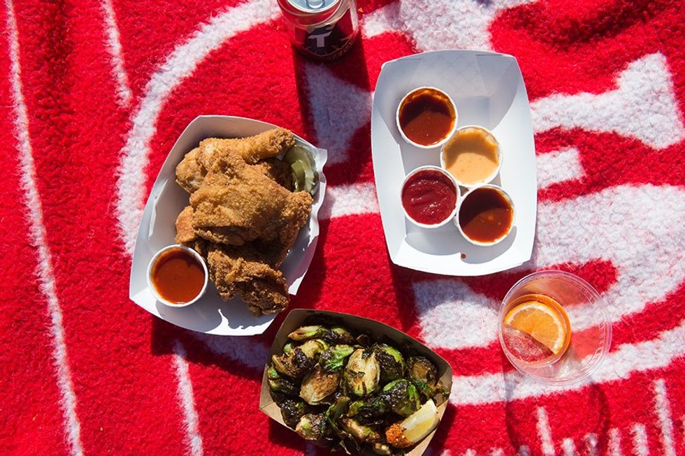 Fried chicken, Brussels sprouts, and sauces on a red picnic blanket.