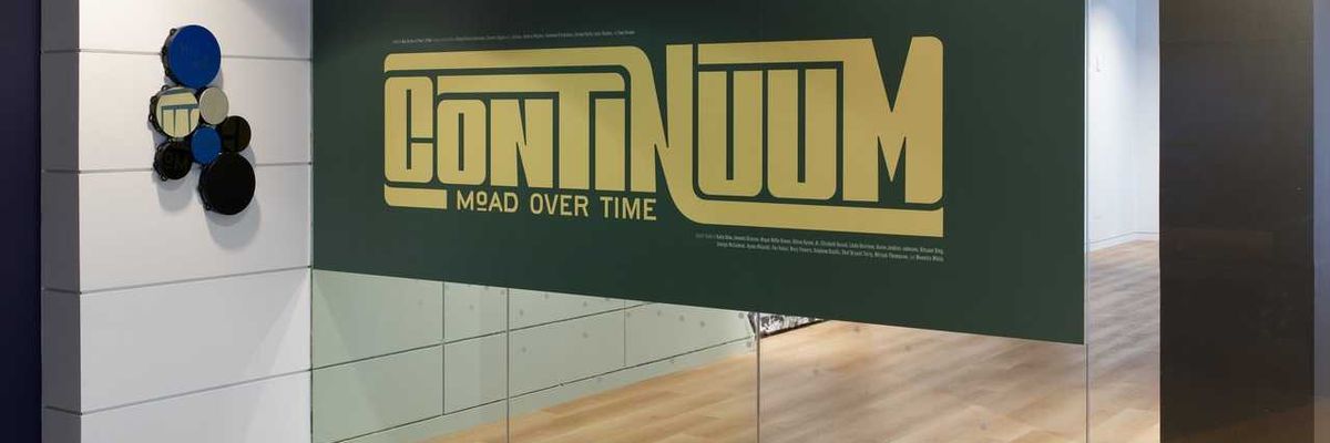 Glass entrance with "Continuum: MoAD Over Time" sign in bold yellow letters.