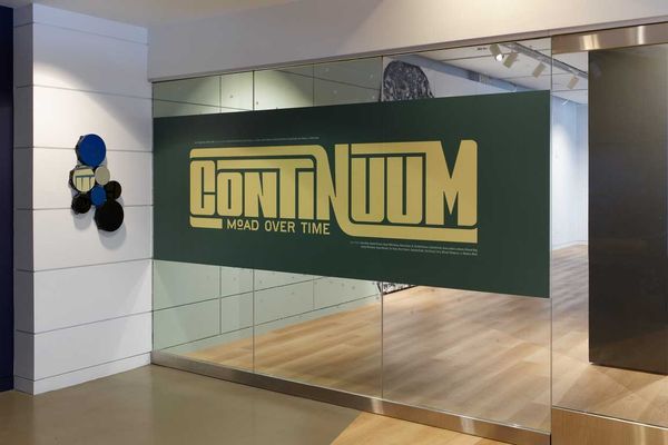 Glass entrance with "Continuum: MoAD Over Time" sign in bold yellow letters.