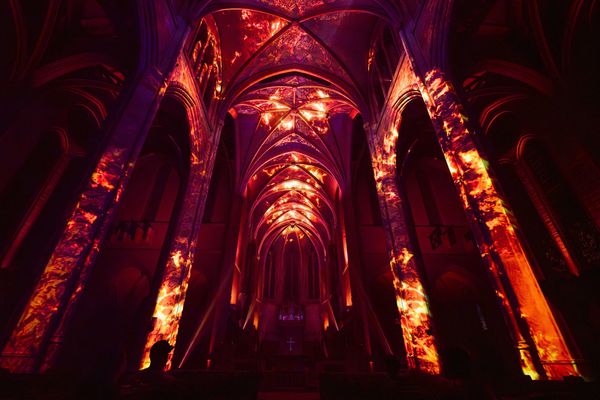 Gothic cathedral interior illuminated with fiery red and orange projections.