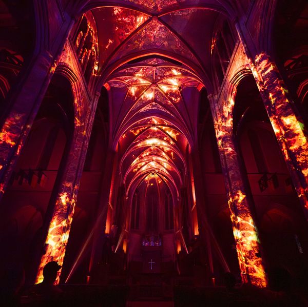 Gothic cathedral interior illuminated with fiery red and orange projections.