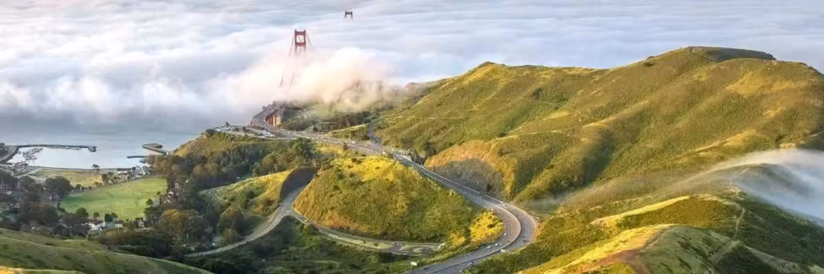 green headlands stretching into the fog with the Golden Gate Bridge peeking out