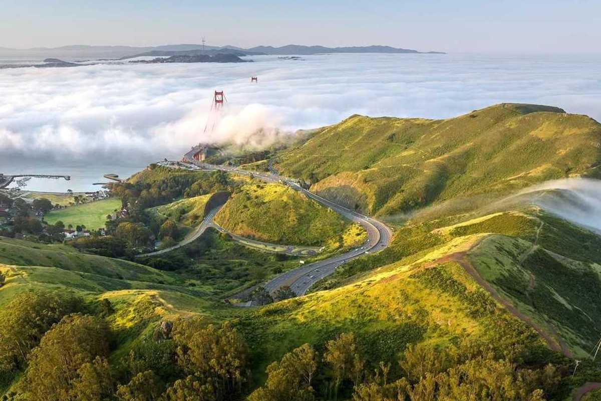 green headlands stretching into the fog with the Golden Gate Bridge peeking out