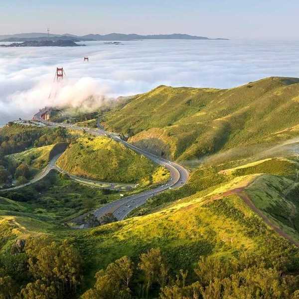 green headlands stretching into the fog with the Golden Gate Bridge peeking out