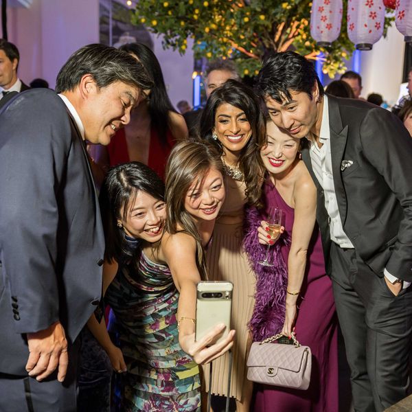 Group of people at a party taking a selfie together, smiling and dressed formally.