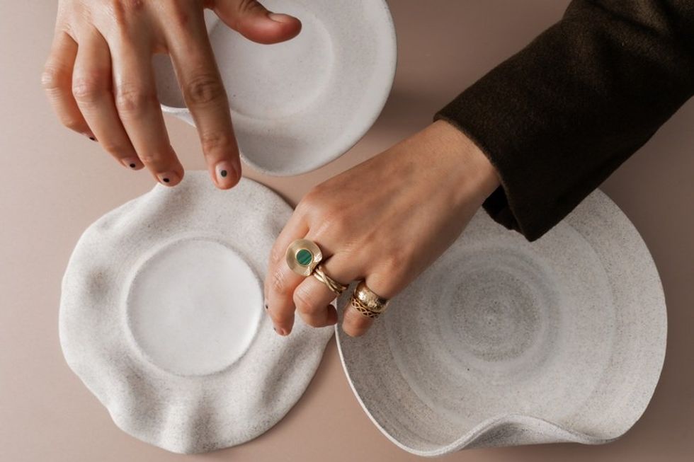 Hands arranging three textured white ceramic plates.