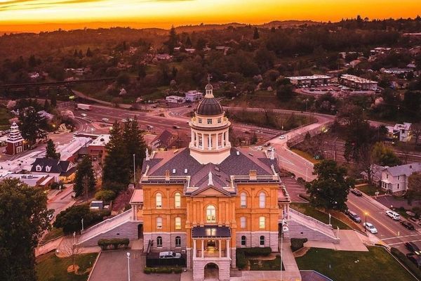 Historic courthouse under vibrant sunset sky, surrounded by roads and greenery.