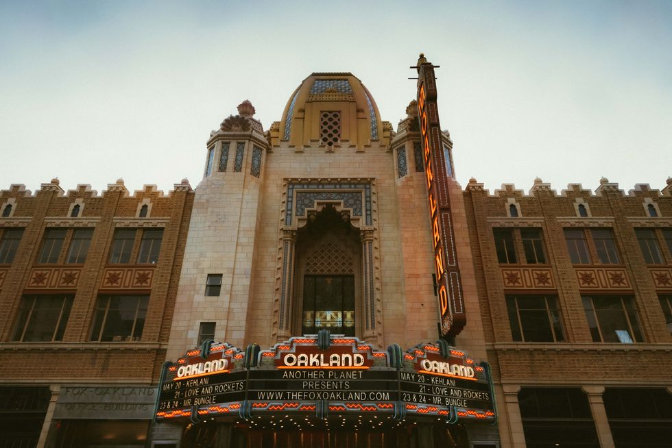 Historic theater with ornate facade and illuminated "Oakland" sign in Art Deco style.