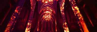 Gothic cathedral interior illuminated with fiery red and orange projections.