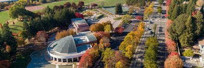 Aerial view of a campus with fall foliage and distant hills.