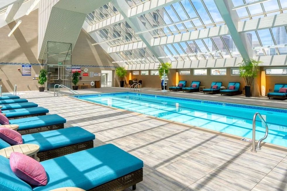 Indoor pool with blue lounge chairs and skylight ceiling.