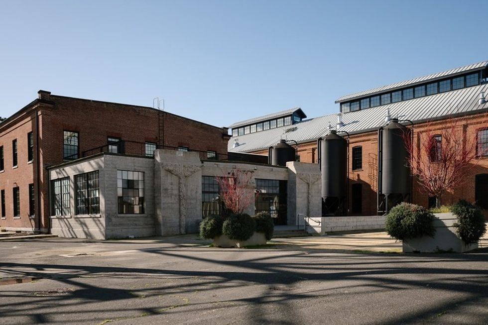 Industrial brick building with large windows and outdoor cylindrical tanks.