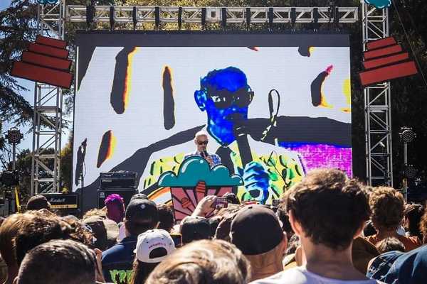 jon waters on stage in front of his own portrait