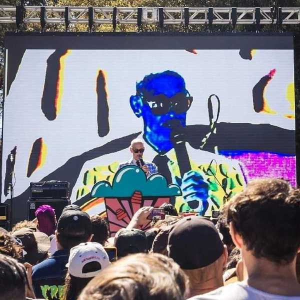 jon waters on stage in front of his own portrait