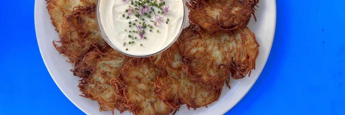 latkes on a plate around a bowl of creme fraiche with flowers on top