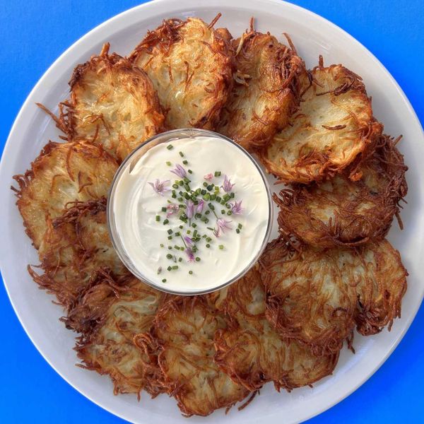 latkes on a plate around a bowl of creme fraiche with flowers on top