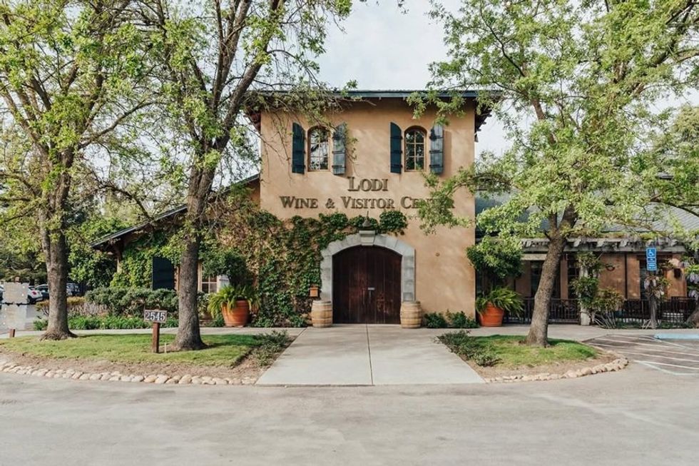 Lodi Wine & Visitor Center surrounded by trees and greenery under a clear sky.