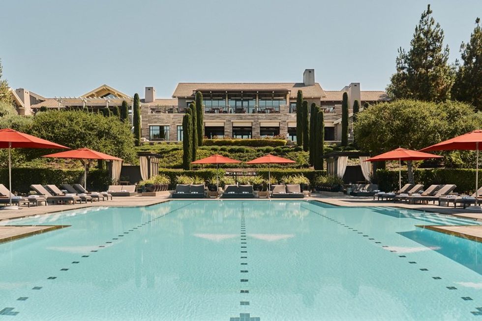 Luxurious poolside view with red umbrellas at an elegant hotel.