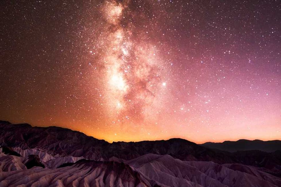 Milky Way galaxy over desert landscape at sunset.