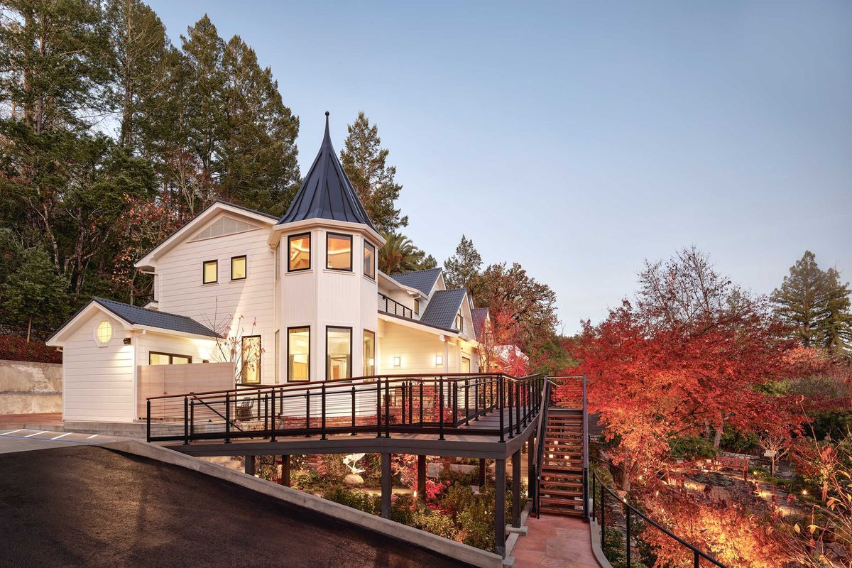 Modern house with a turret, surrounded by autumn trees and enhanced by evening lighting.