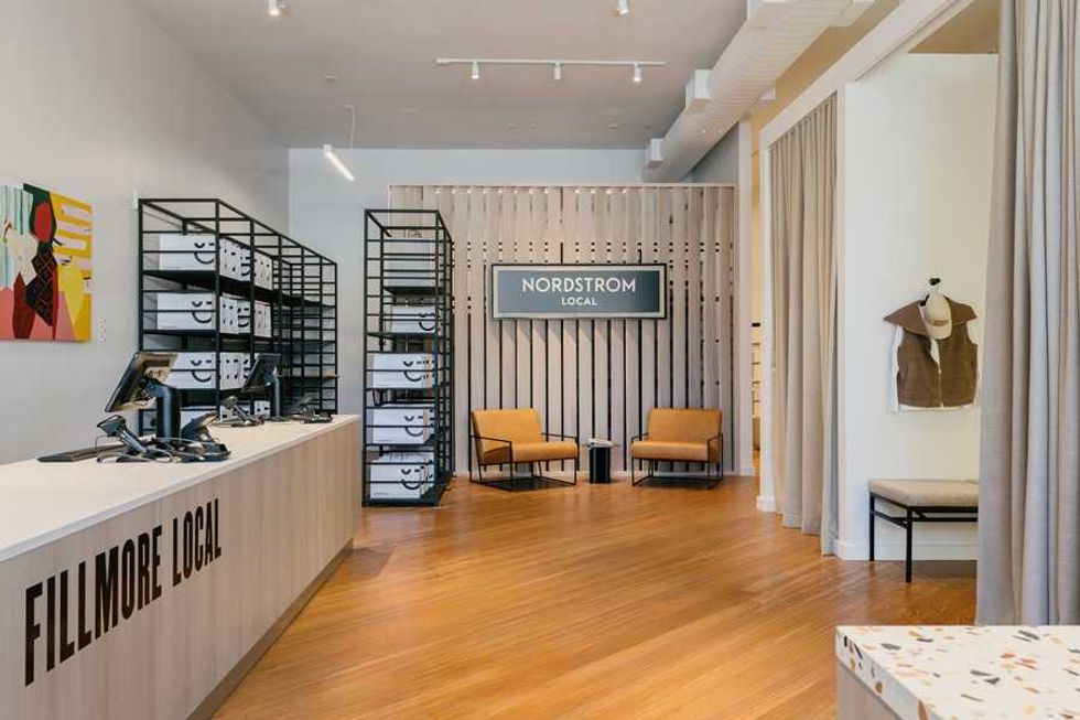 Modern store interior with seating, stacked boxes, and "Nordstrom Local" sign.
