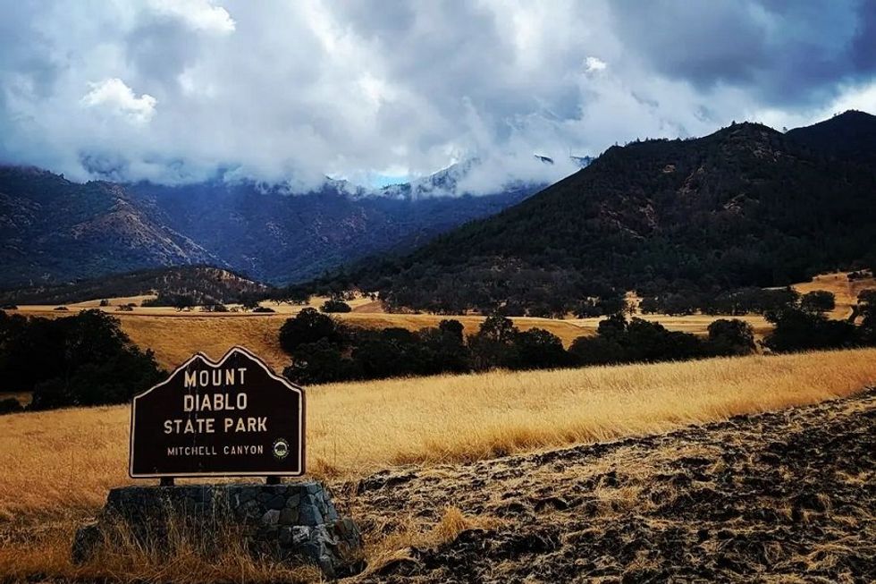 Mount Diablo State Park sign with cloudy mountains in the background.