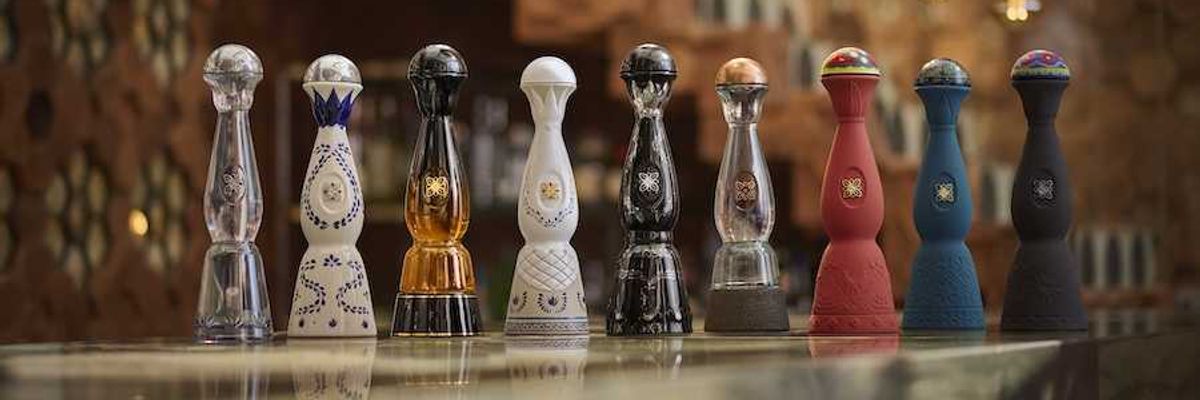 Nine ornate tequila bottles on a bar under pendant lights.