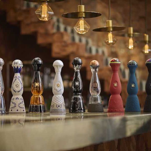 Nine ornate tequila bottles on a bar under pendant lights.