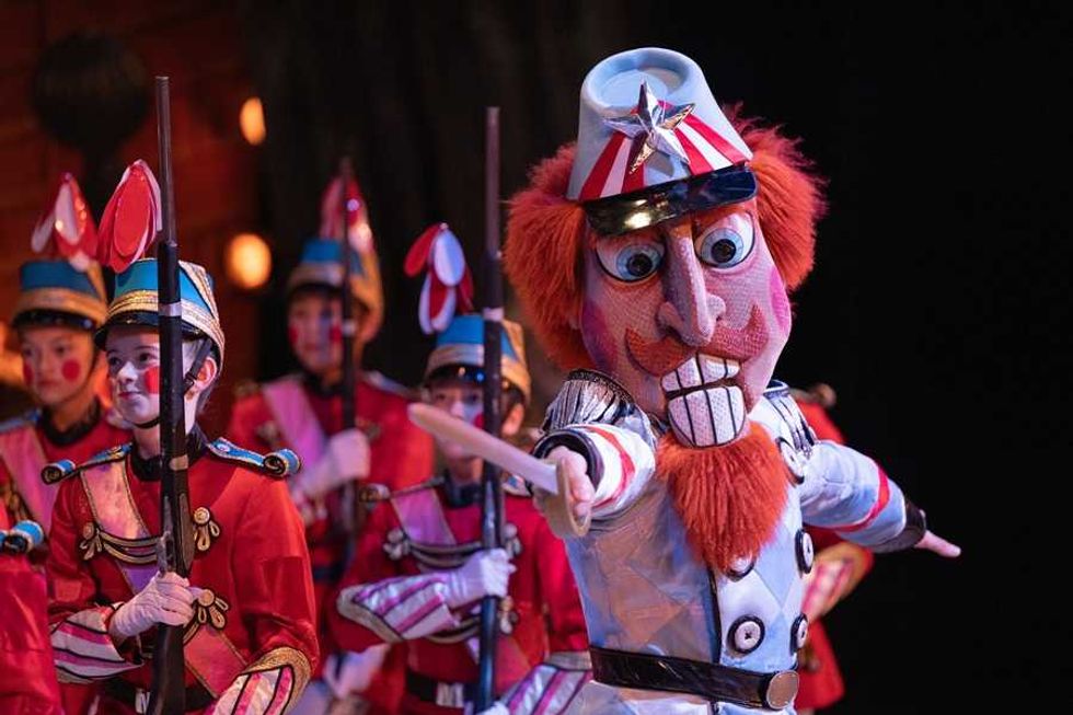 Nutcracker with large head leads toy soldiers on stage during a performance.