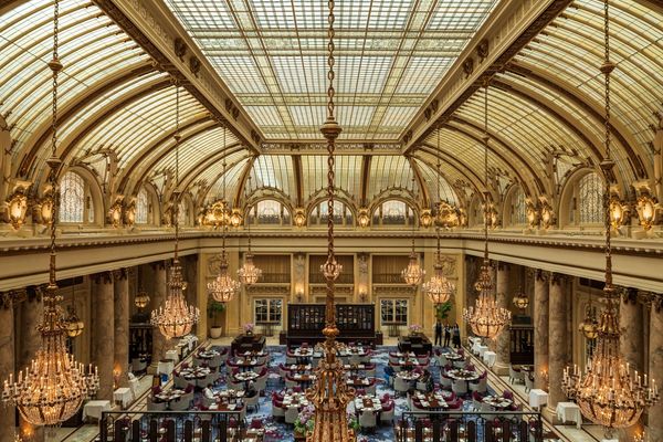 Opulent dining room with chandeliers under a grand, arched glass ceiling.