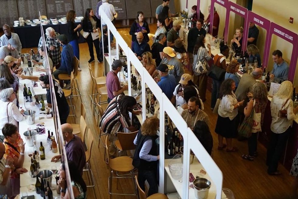 People at a wine tasting event, browsing and sampling various wines from exhibitors.