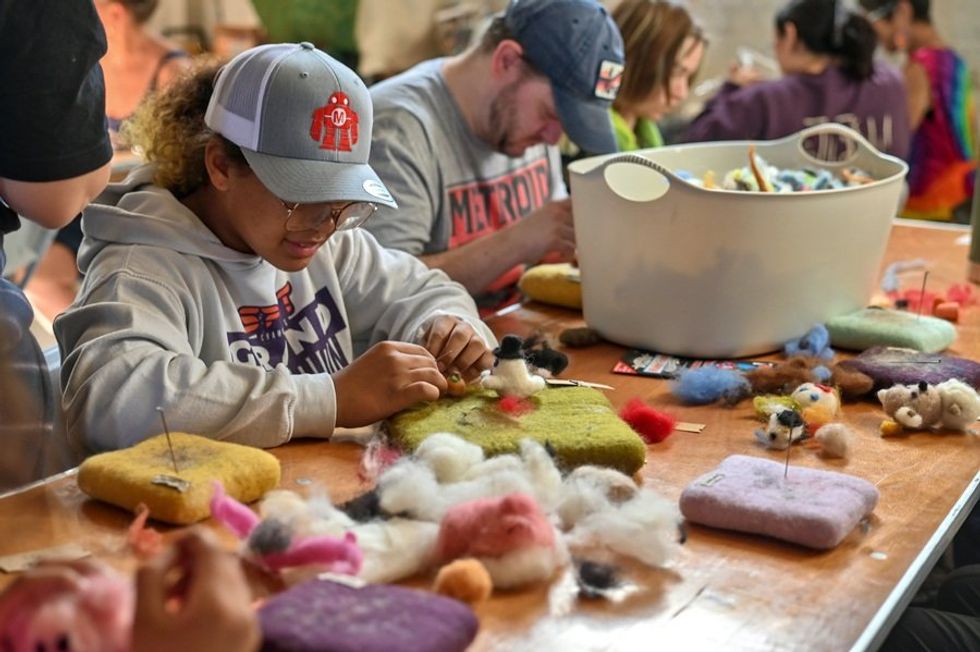 People crafting with colorful wool at a workshop table.