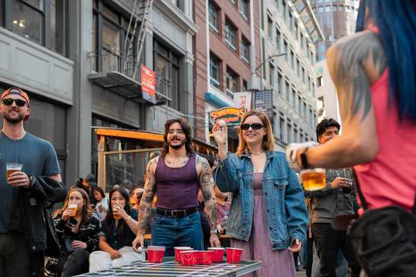 people playing beer pong on a downtown street