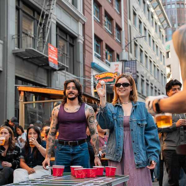 people playing beer pong on a downtown street