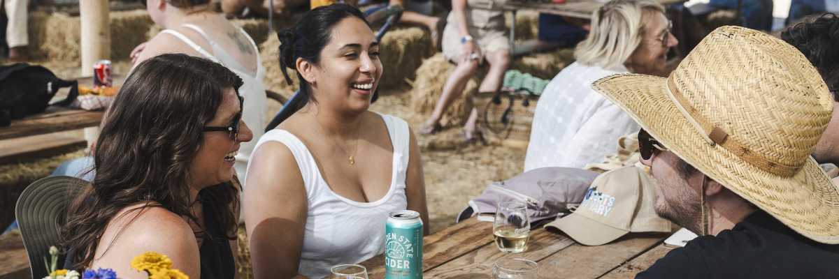 people sharing drinks at a picnic table in a pavilion at an apple festival