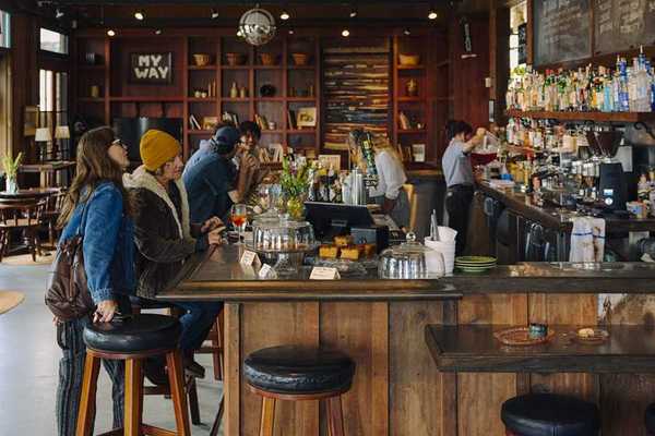 people sitting at a cozy, rustic bar with stylish shelves in the background