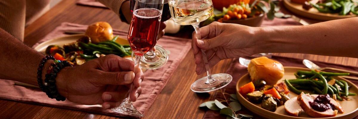 People toasting with wine at a festive, autumn-themed dinner table.