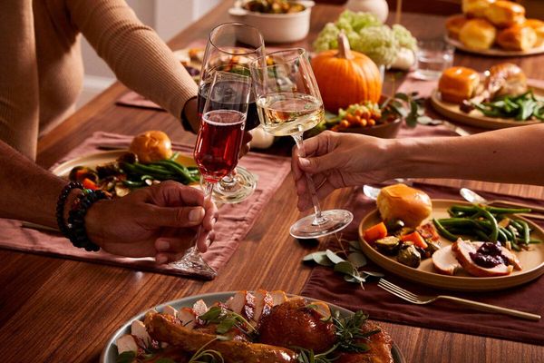 People toasting with wine at a festive, autumn-themed dinner table.