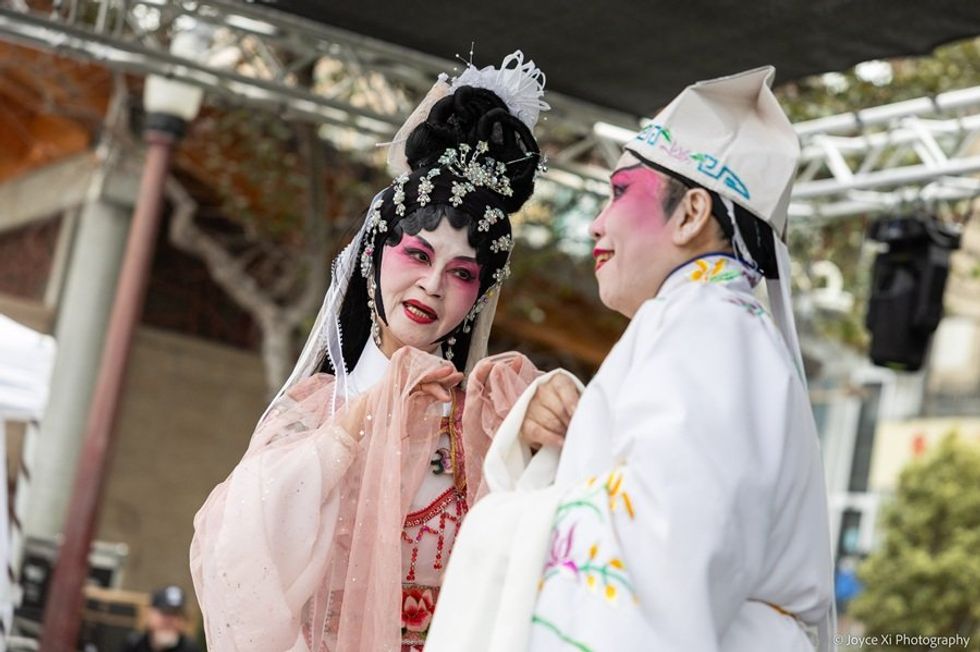 Performers in traditional Chinese opera costumes and makeup on stage.