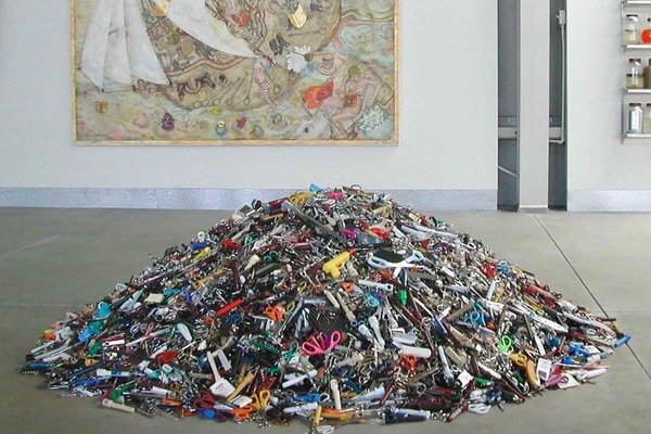 Pile of confiscated scissors and tools at airport security in a gallery space.
