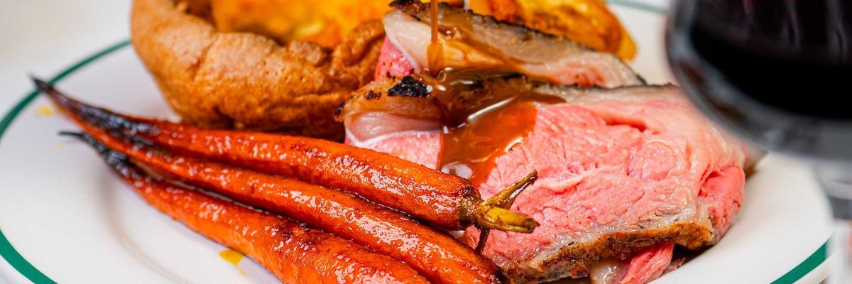 roast meat with Yorkshire pudding and roast carrots being drizzled with jus