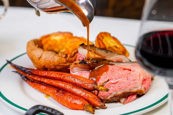 roast meat with Yorkshire pudding and roast carrots being drizzled with jus