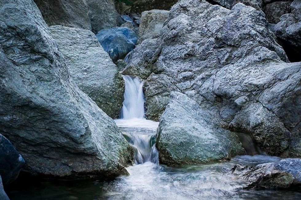 Small waterfall flowing between large grey rocks.