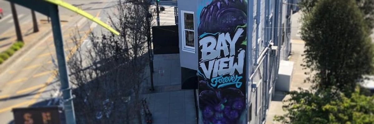Street mural of a superhero with "Bay View Forever" text on an urban building wall.