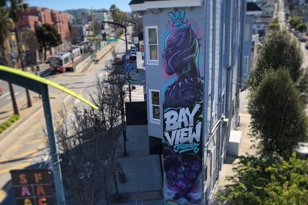 Street mural of a superhero with "Bay View Forever" text on an urban building wall.